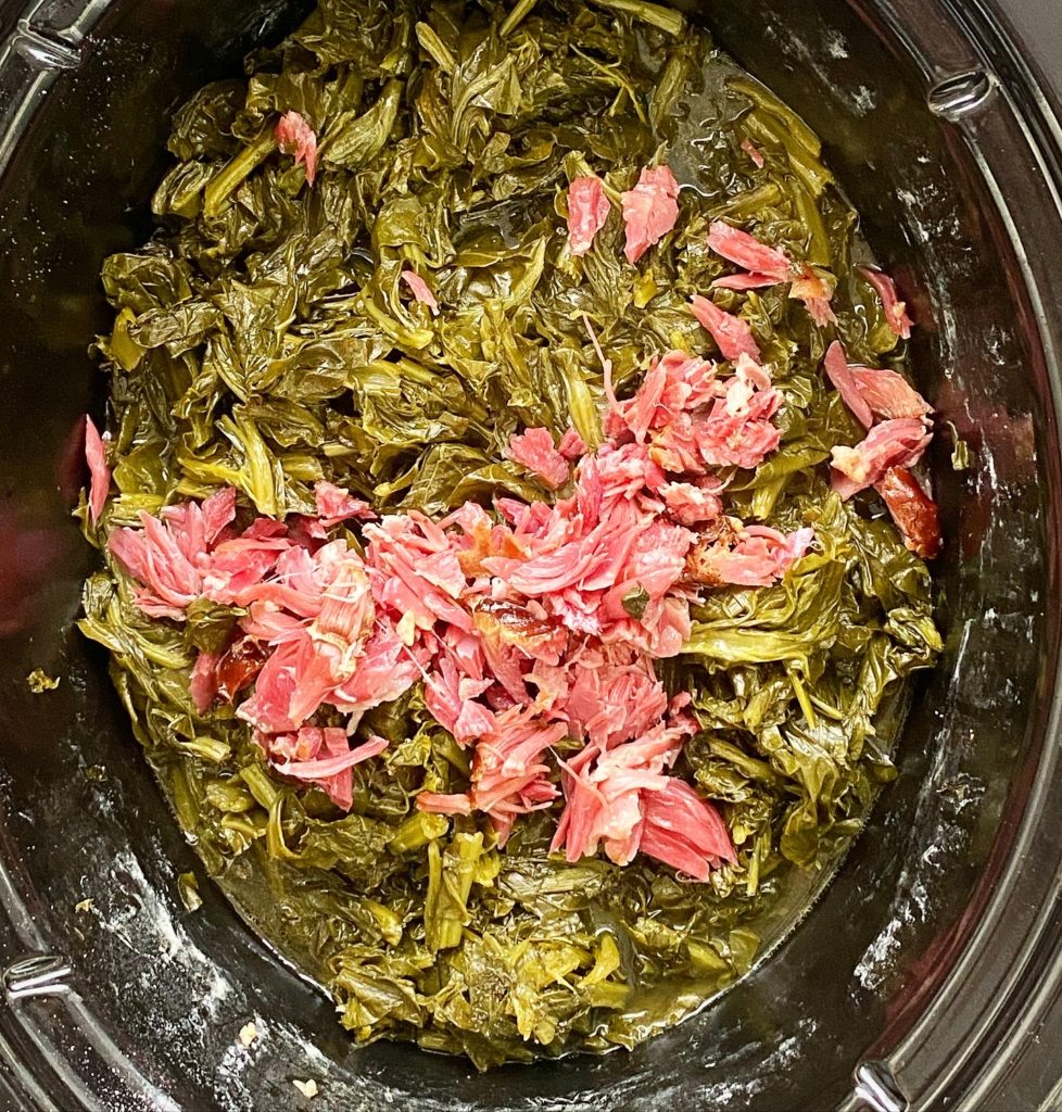cooked greens with shredded ham hock meat in the slow cooker