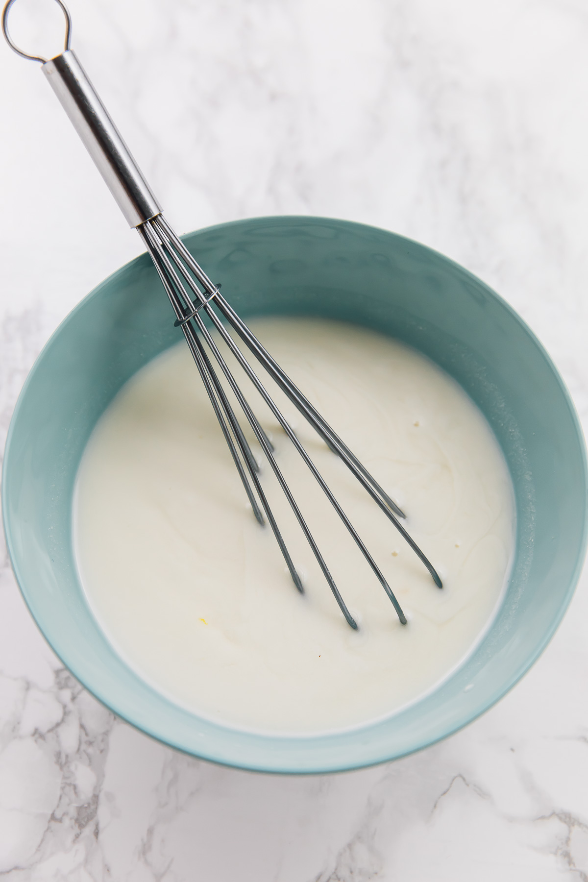 A bowl of vegan buttermilk, with a whisk stuck in it