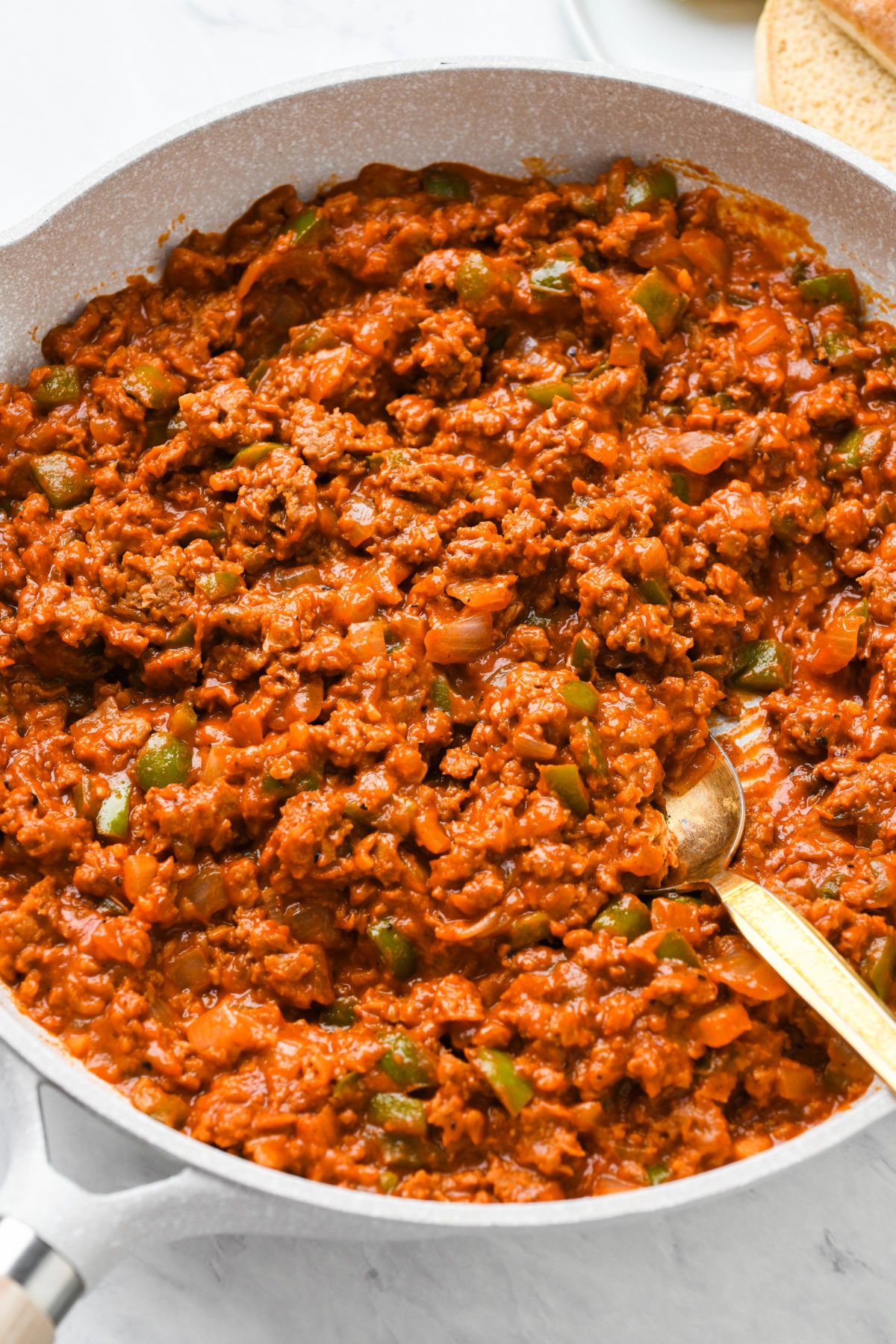 A pan with sloppy joes mixture cooking in it, and a serving spoon in the pan