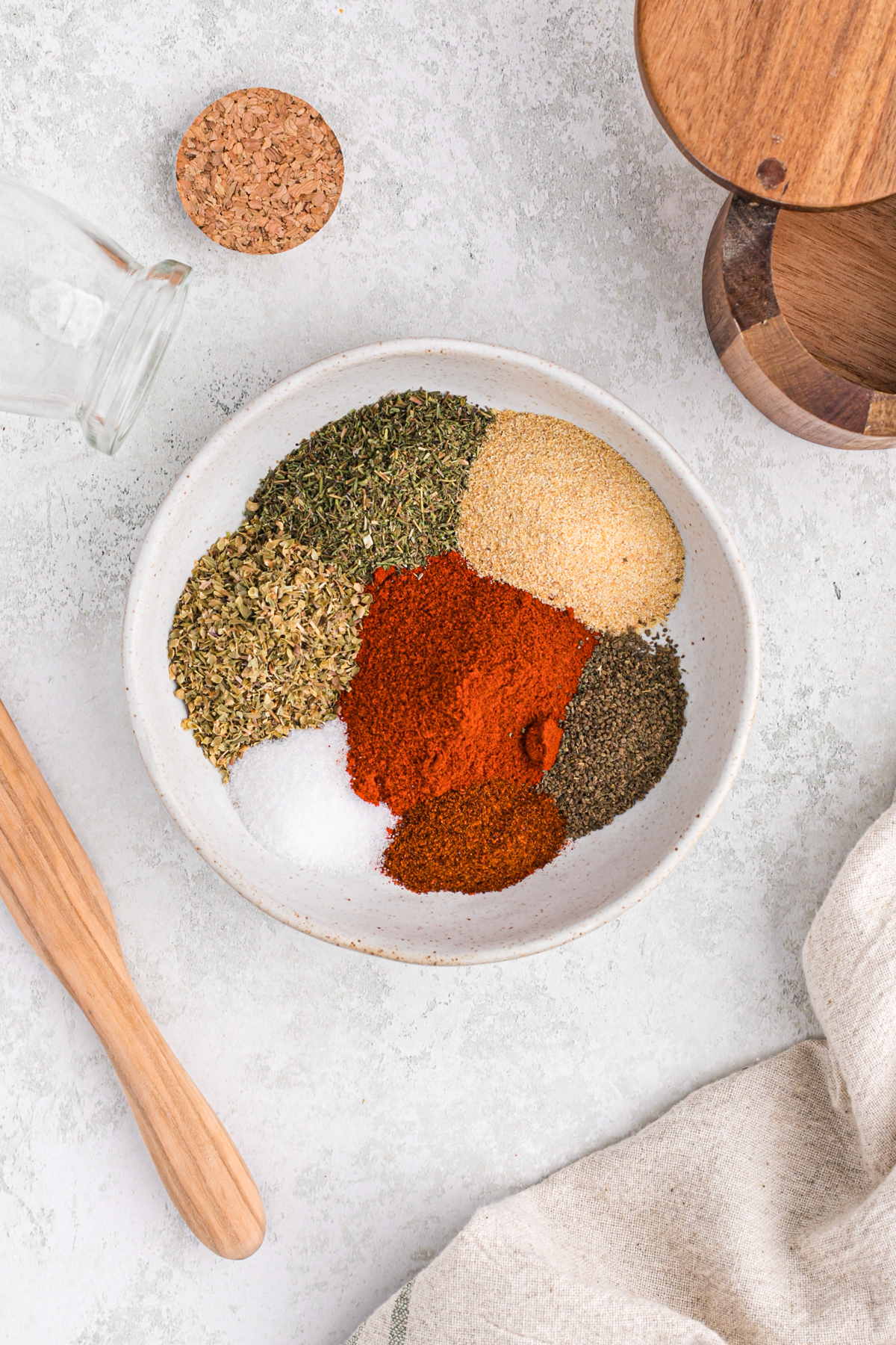 Several spices and dried herbs in a bowl before combining