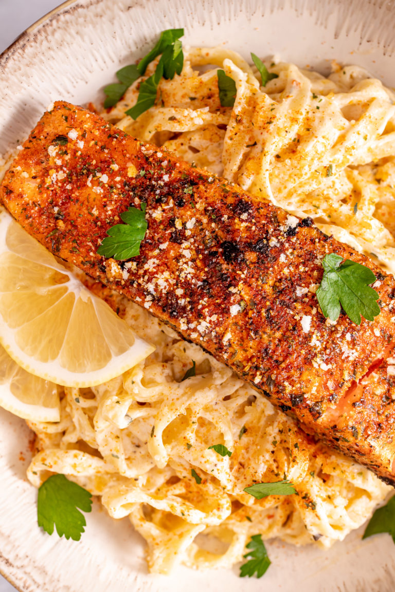 cajun salmon Alfredo pasta on a plate with lemon slices