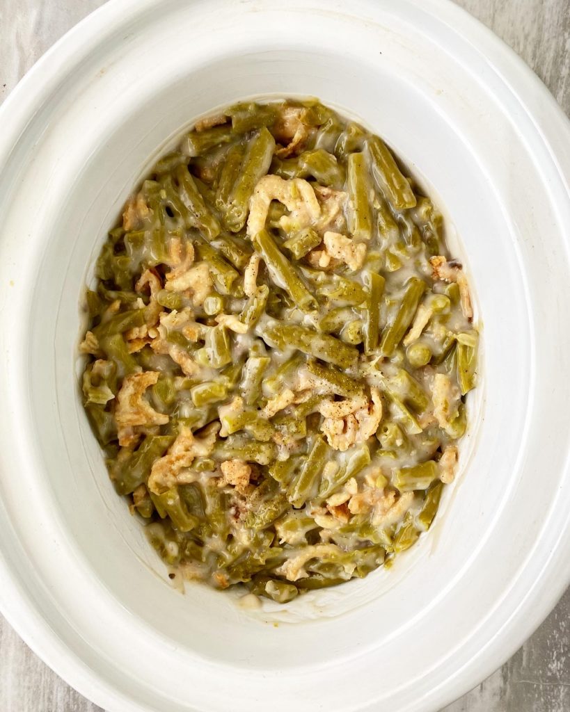 overhead shot of uncooked green bean casserole in a white slow cooker