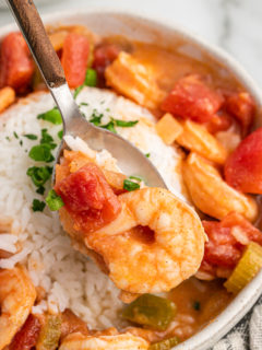 A spoon of shrimp being lifted from etouffee.