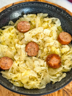 cooked cabbage and sausage in a black bowl