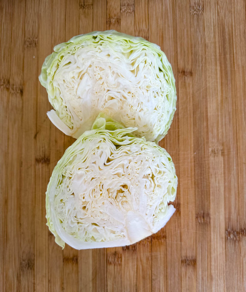 head of cabbage sliced in half on a cutting board