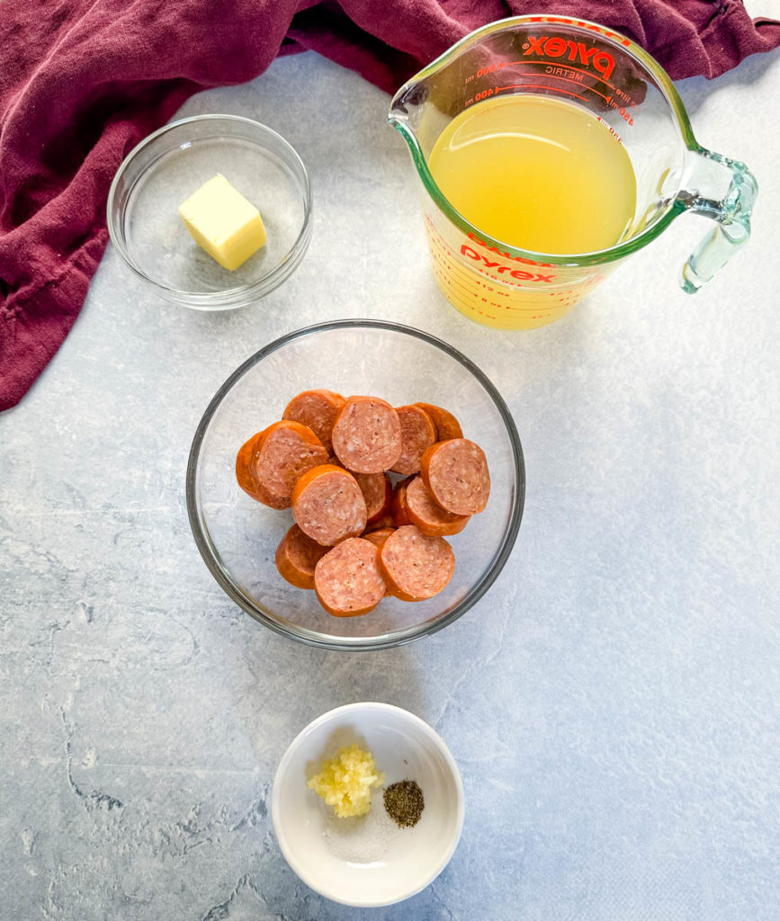 butter, broth, sausage rounds, and spices in separate glass bowls