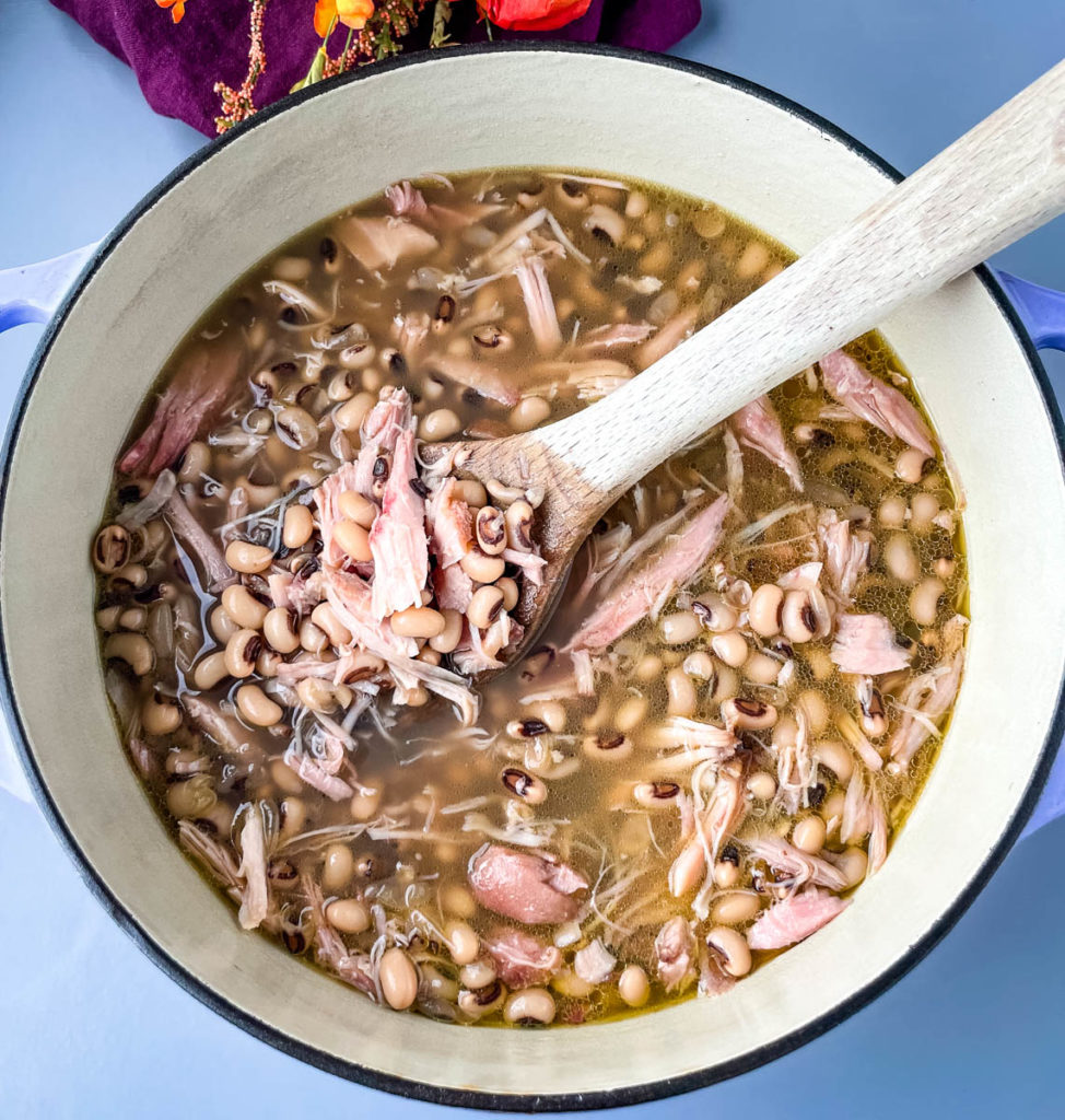 Southern black eyed peas with smoked turkey and a wooden spoon in a Dutch oven pot