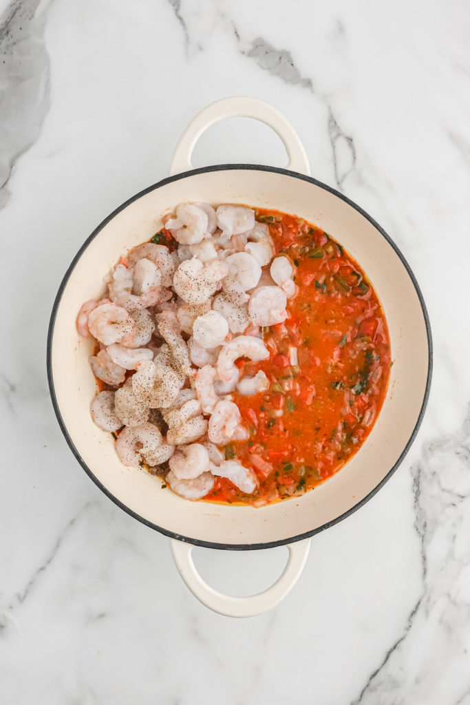 Tomato sauce cooking with raw shrimp added