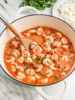 Cooked shrimp in a tomato sauce being spooned