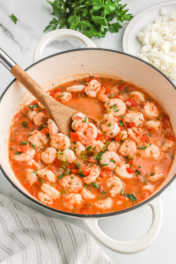 Cooked shrimp in a tomato sauce being spooned