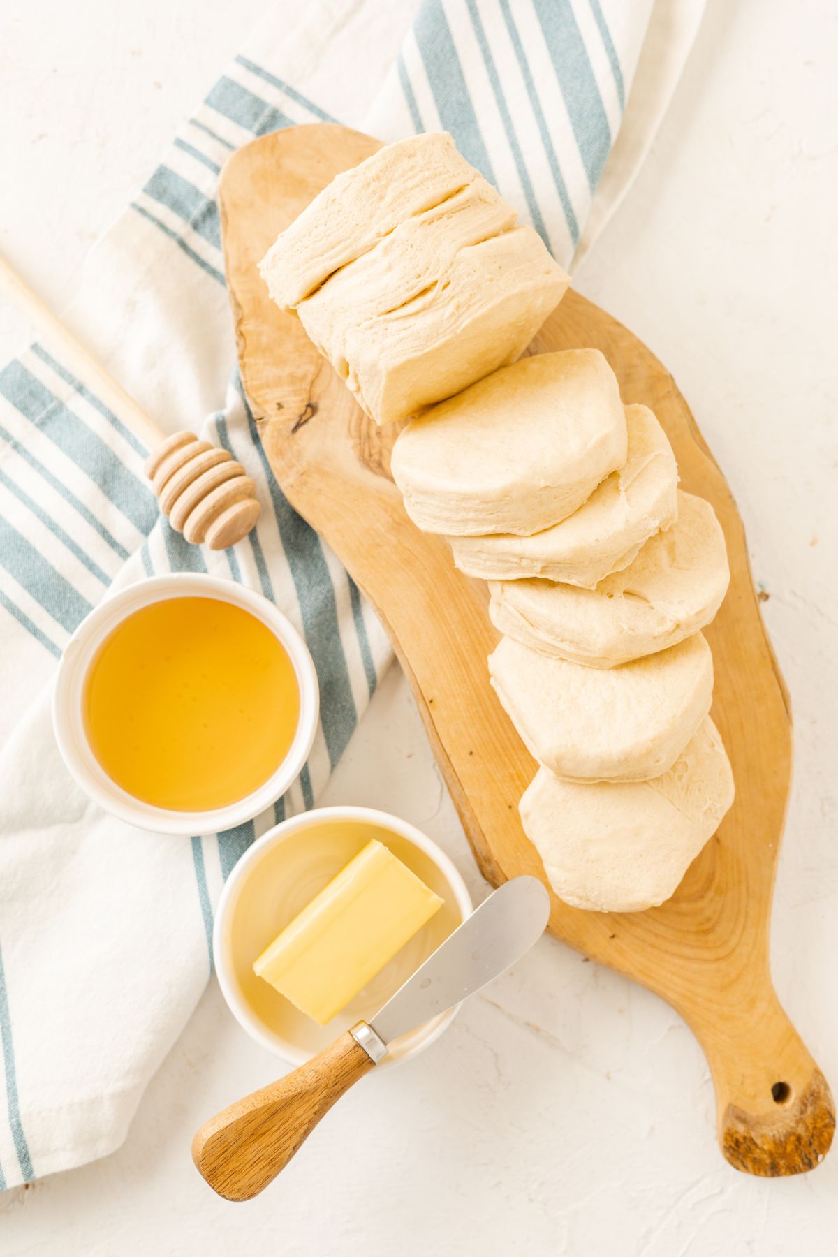 butter and honey on separate bowls and pillsbury grands biscuits on a wooden chopping board