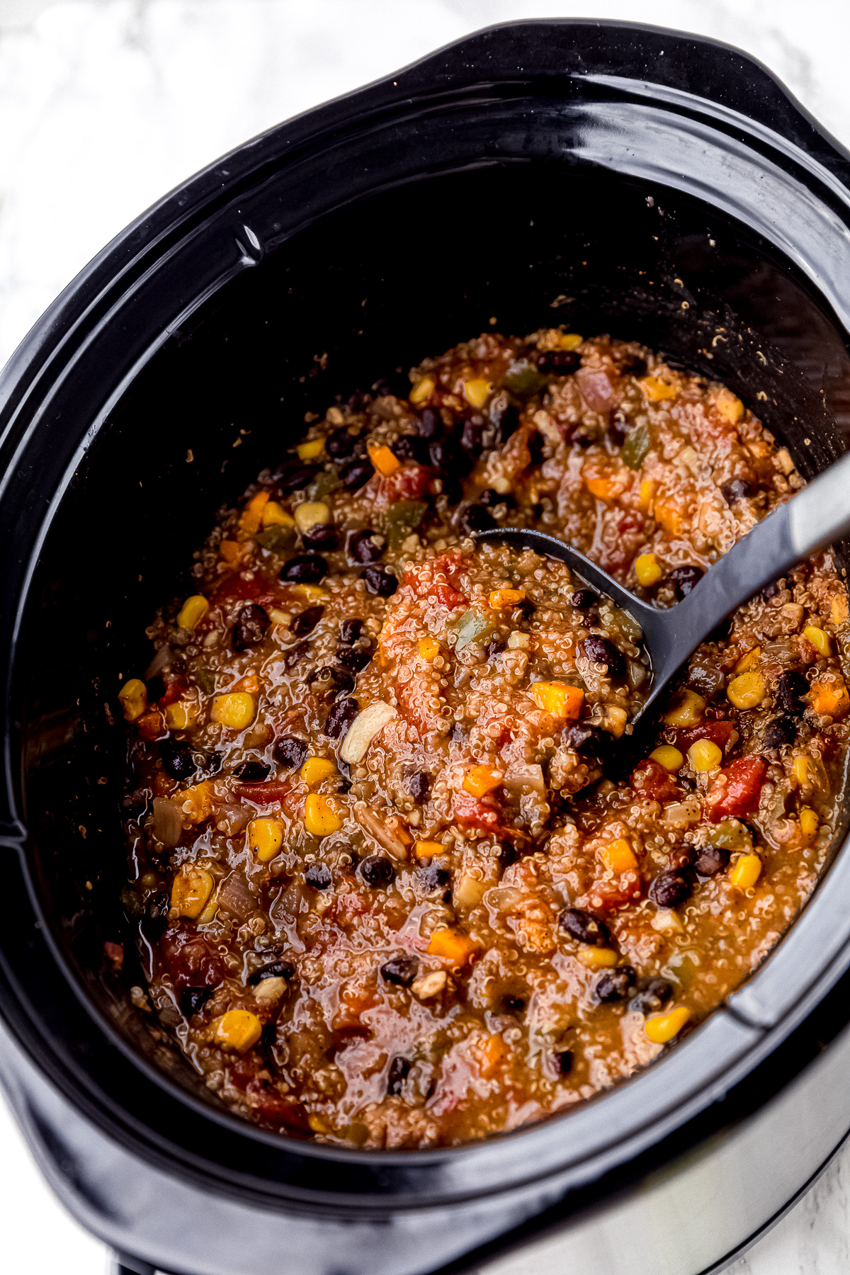 A full ladle in a slow cooker full of chili