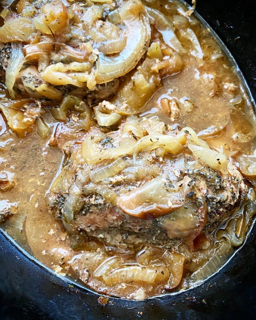 overhead shot of cooked Crockpot Pork Chops, Apples & Onions in a black slow cooker