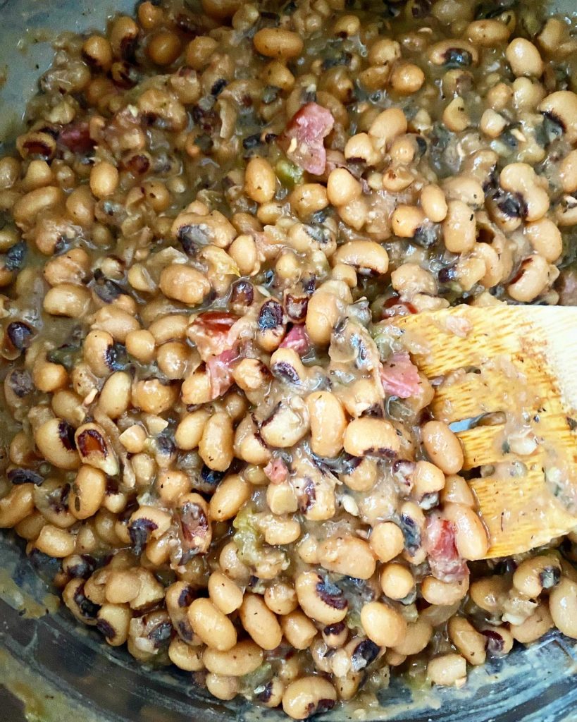 close up shot of cooked hoppin john in the instant pot with a wooden spoon