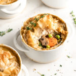 A pot pie with a sprig of thyme on top, next to three other pot pies