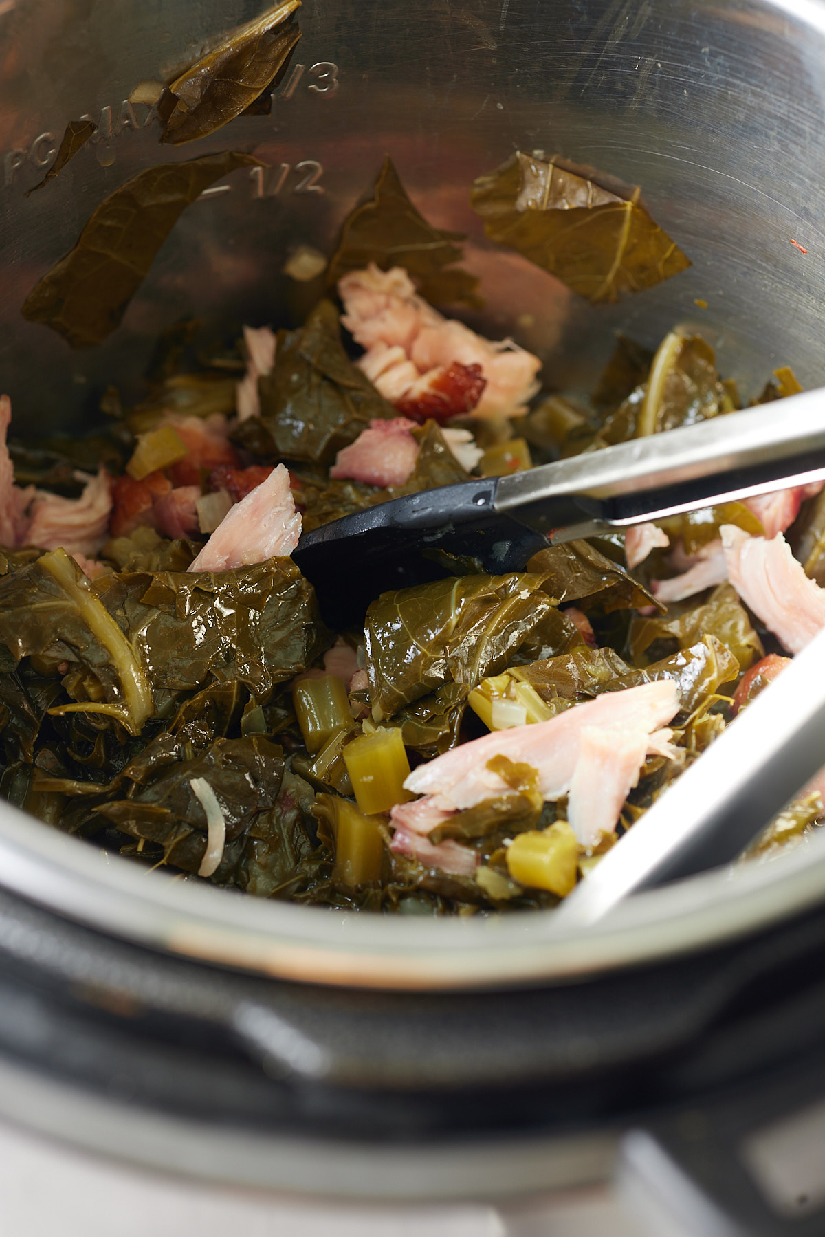 collard greens in instant pot with tongs inside of it