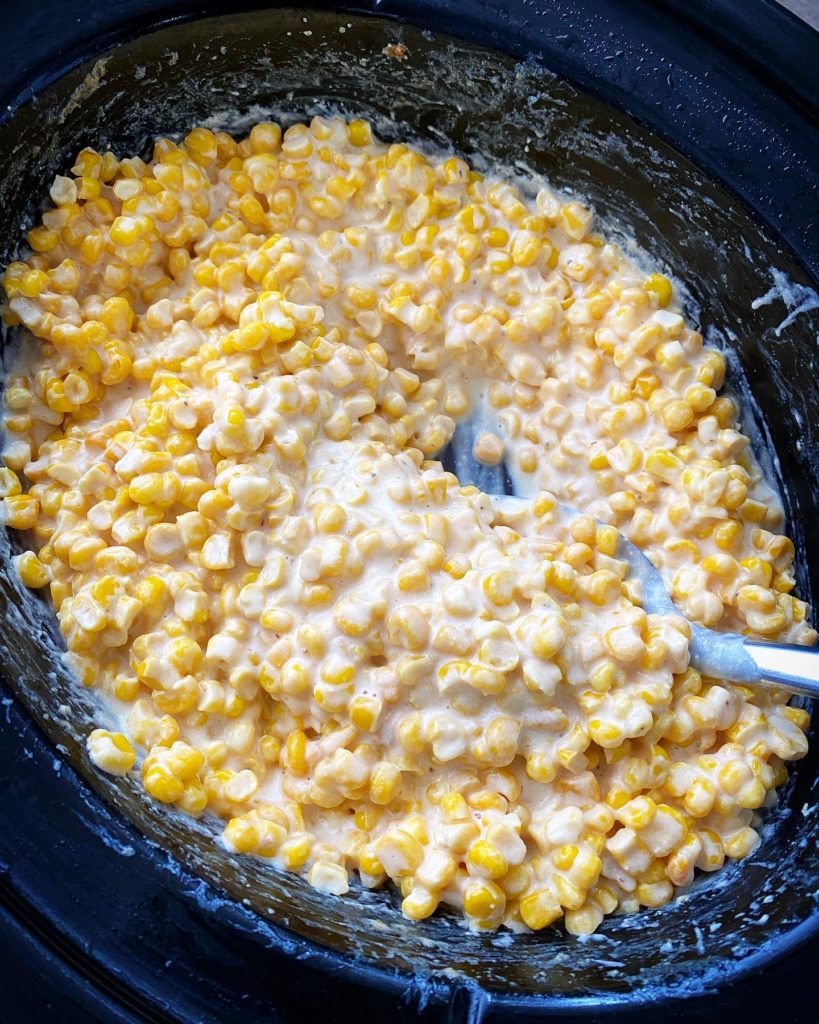 overhead shot of cooked creamed corn in a black slow cooker