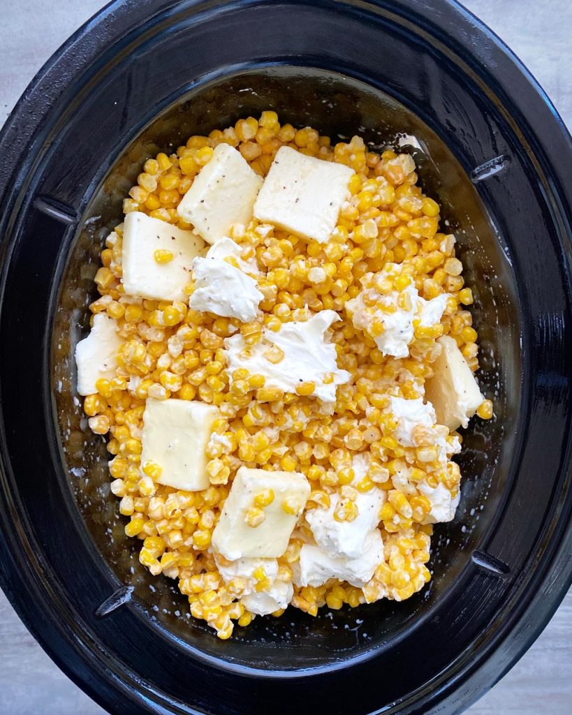 overhead shot of uncooked creamed corn in a black slow cooker, unstirred