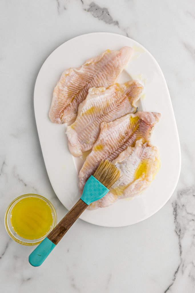 Fish being brushed with oil and butter