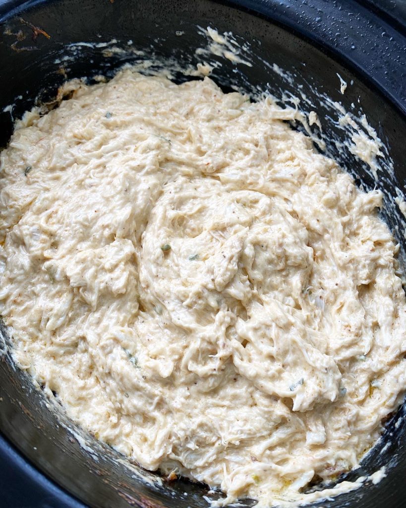overhead shot of cooked hot crab dip in a black slow cooker