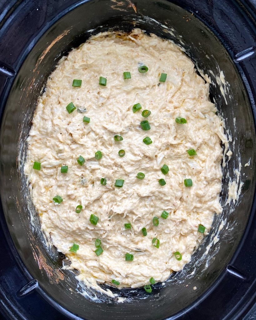overhead shot of cooked hot crab dip in a black slow cooker