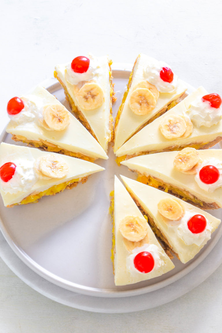 banana split pie with fresh bananas and cherries on a white plate