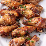 honey garlic chicken wings on white platter with garnish