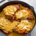 smothered pork chops with gravy in a cast iron skillet