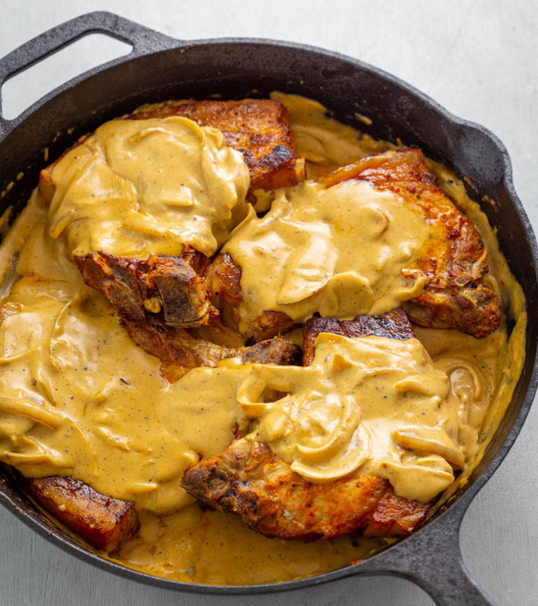smothered pork chops with gravy in a cast iron skillet