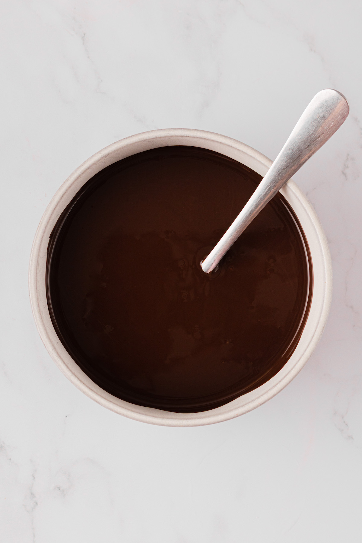 Overhead view of melted chocolate in bowl with spoon