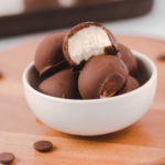 Vegan bon bons in small bowl, with one cut open to show vanilla filling