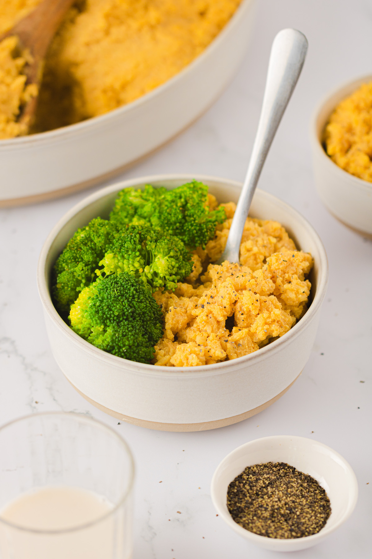 Bowl of vegan cheesy rice with steamed broccoli