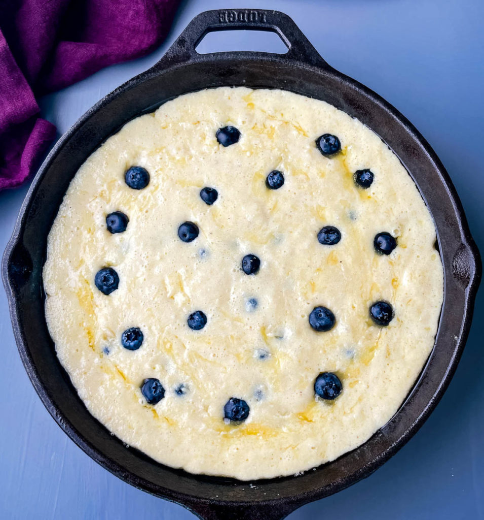 cornbread batter in a cast iron skillet with blueberries
