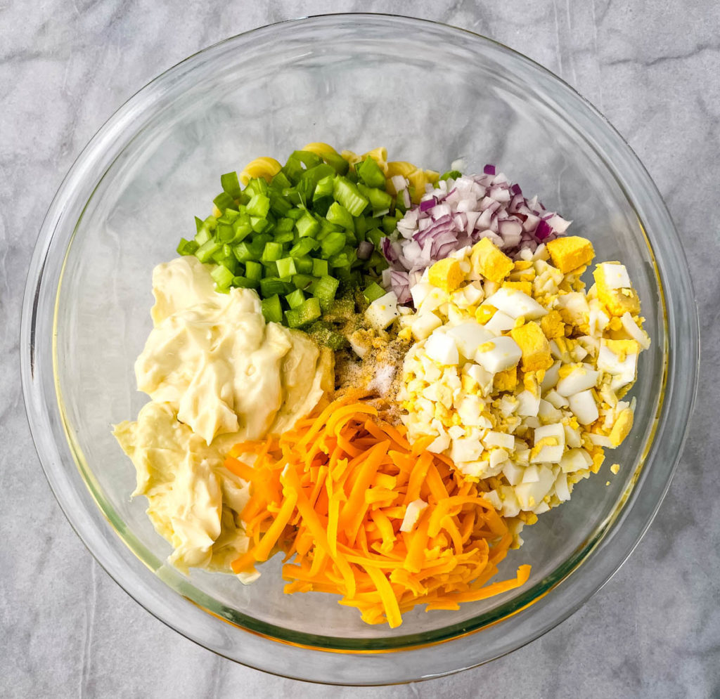 shredded cheese, chopped onions, boiled eggs, and spices in a glass bowl