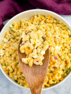 macaroni salad in a white bowl with a wooden spoon