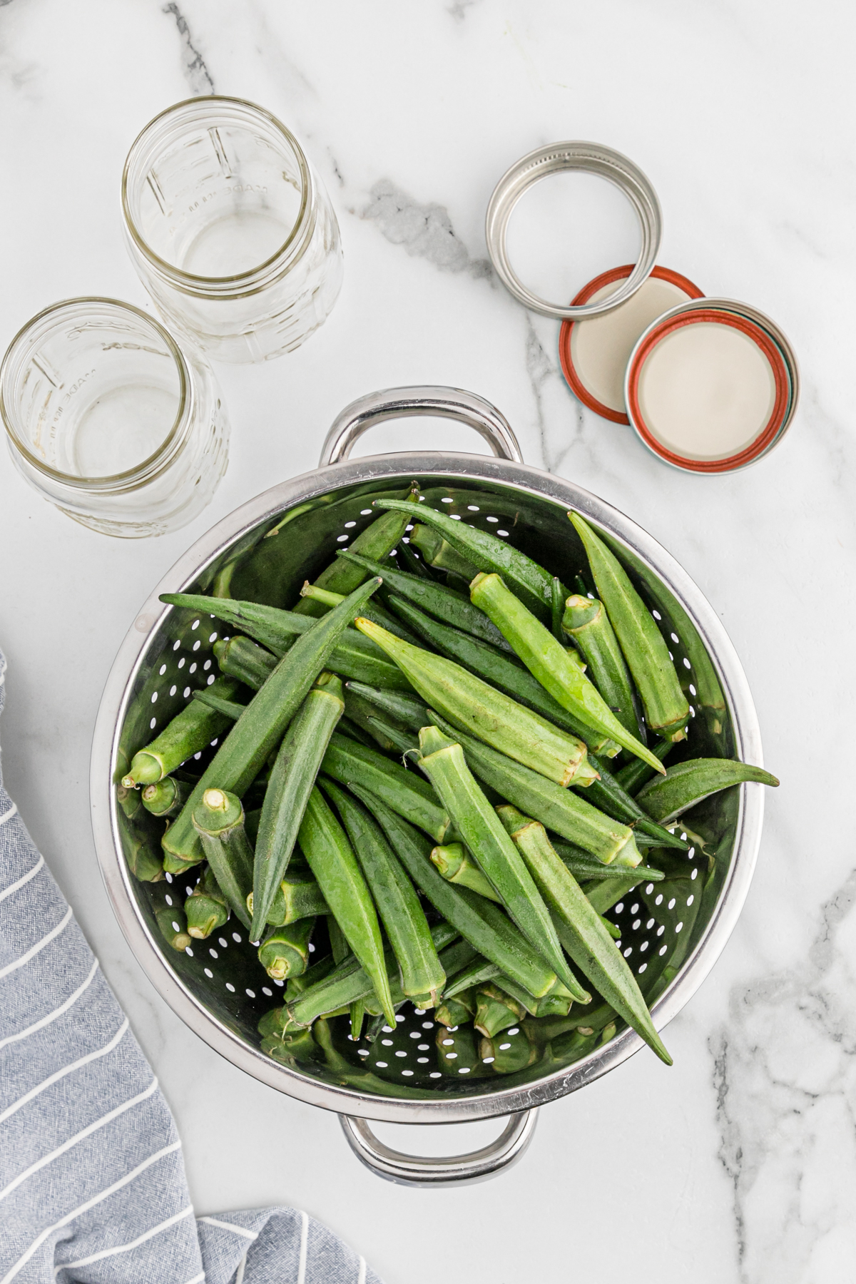 Okra pods in a metal strainer.