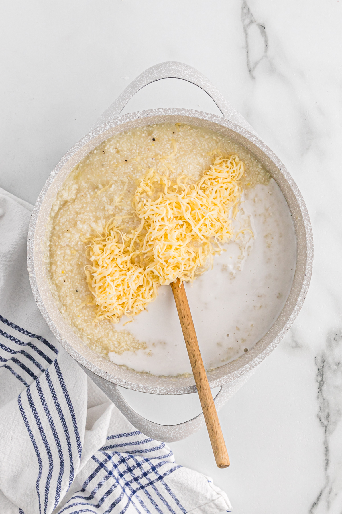 Shredded gouda and dry grits added to a pot of hot milk.