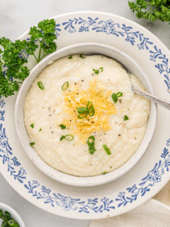 Bowl of smoked gouda grits topped with cheese and green onions.