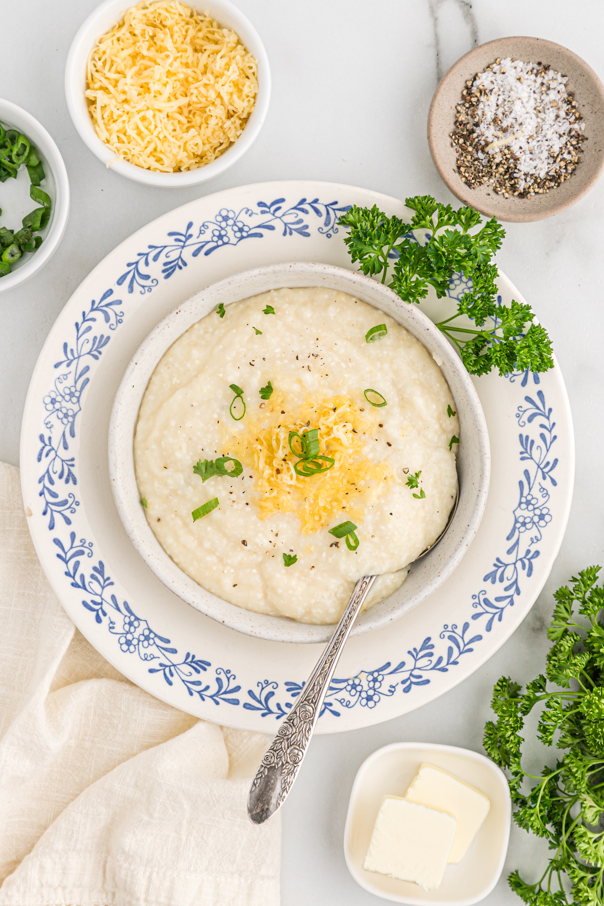 Bowl of smoked gouda grits topped with cheese and green onions.