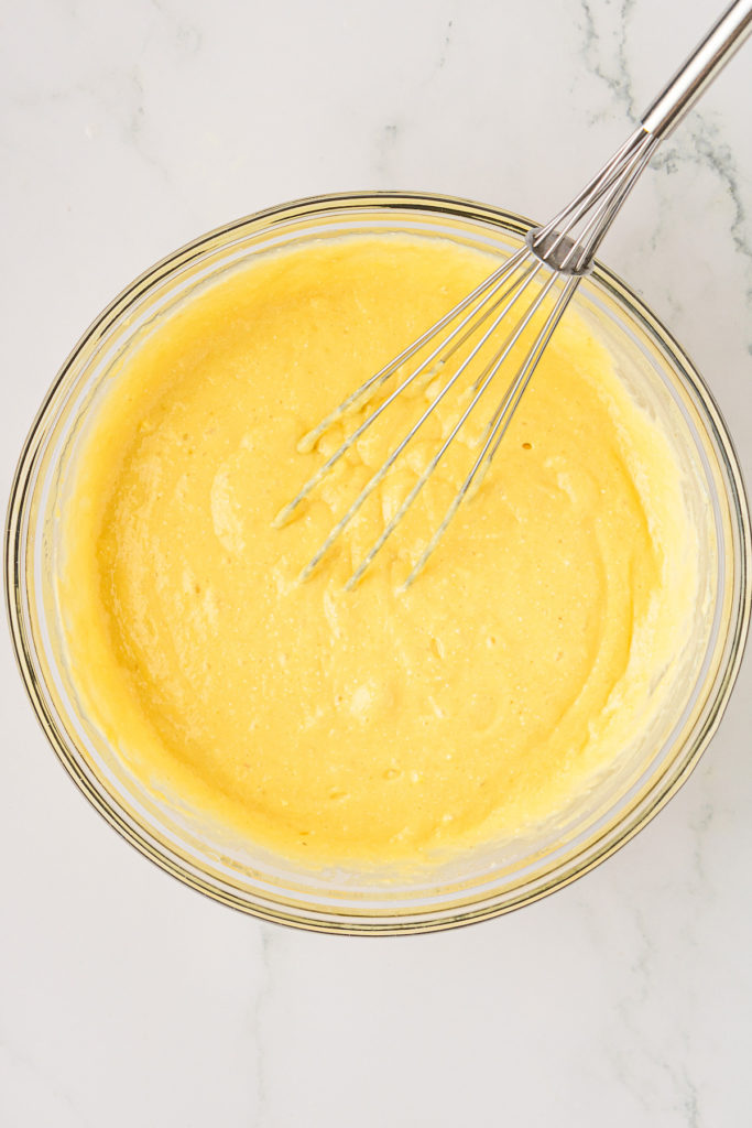 Overhead view of cake batter in mixing bowl with whisk