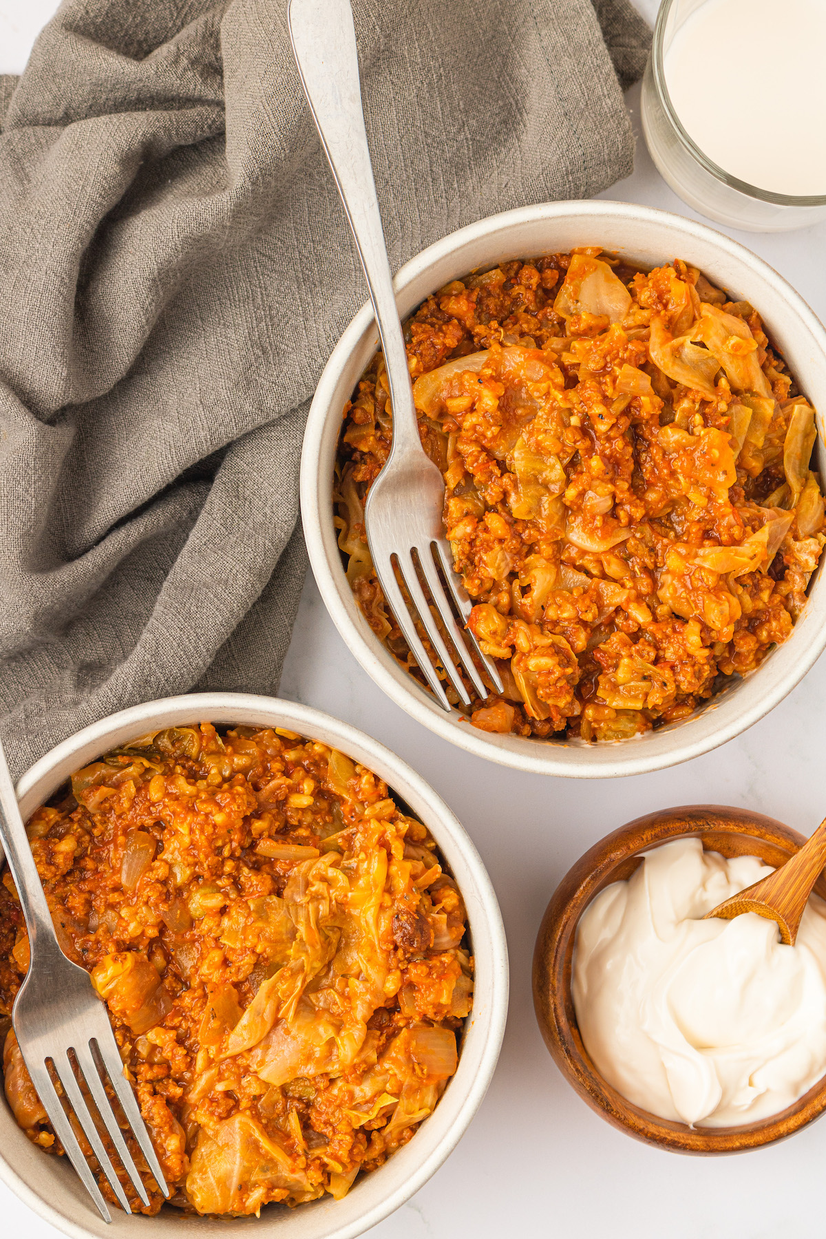 Overhead view of 2 bowls of vegan unstuffed cabbage rolls with forks