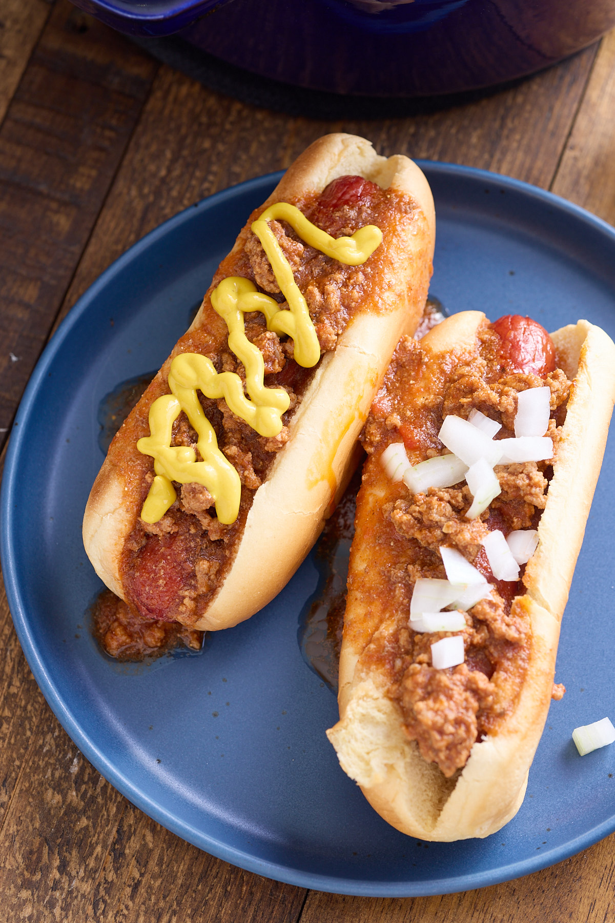 hot dogs with chili and mustard on plate

