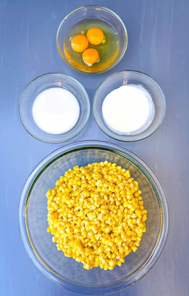 whole kernel corn, eggs, heavy cream, and milk in separate glass bowls