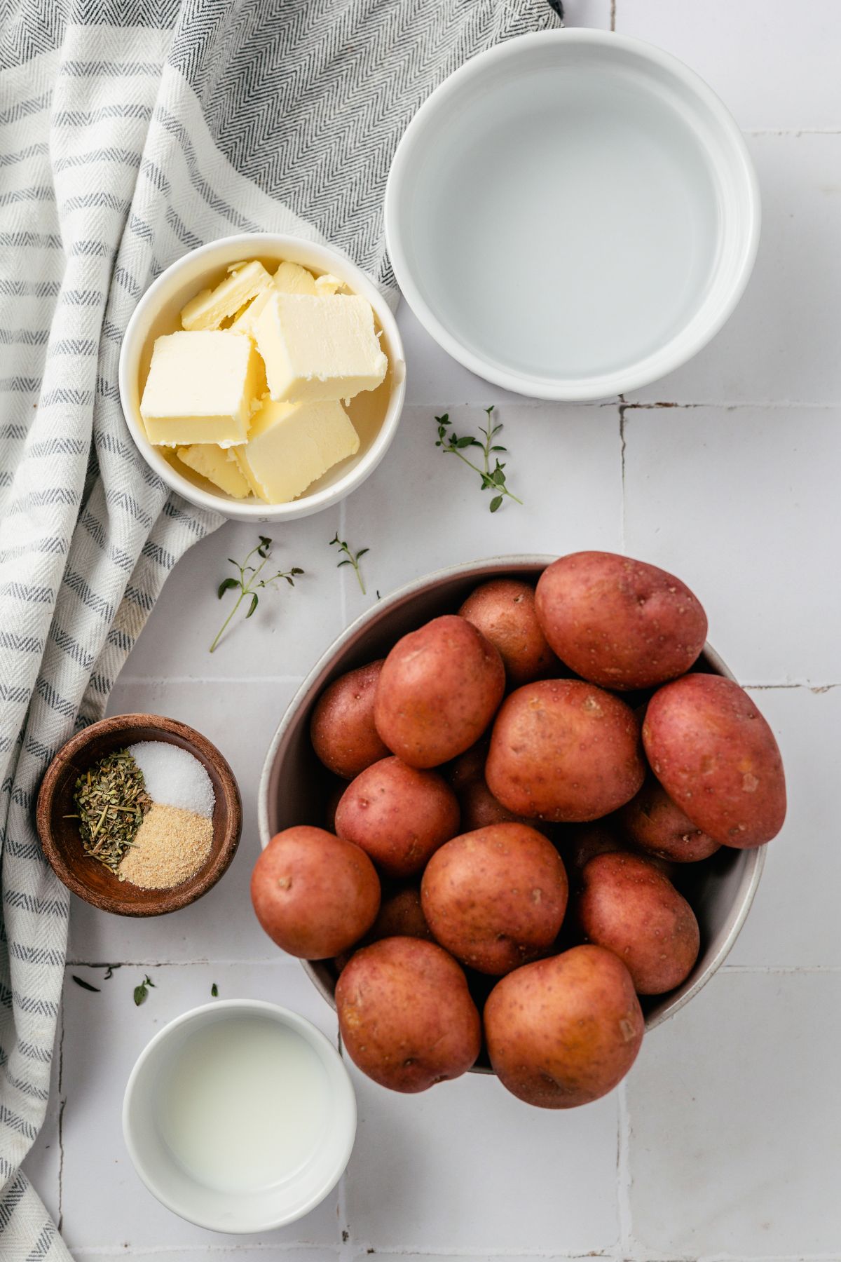 ingredients to make red skin mashed potatoes like red potatoes, butter, water, herb seasoning, milk, sea salt and garlic powder in separate bowls