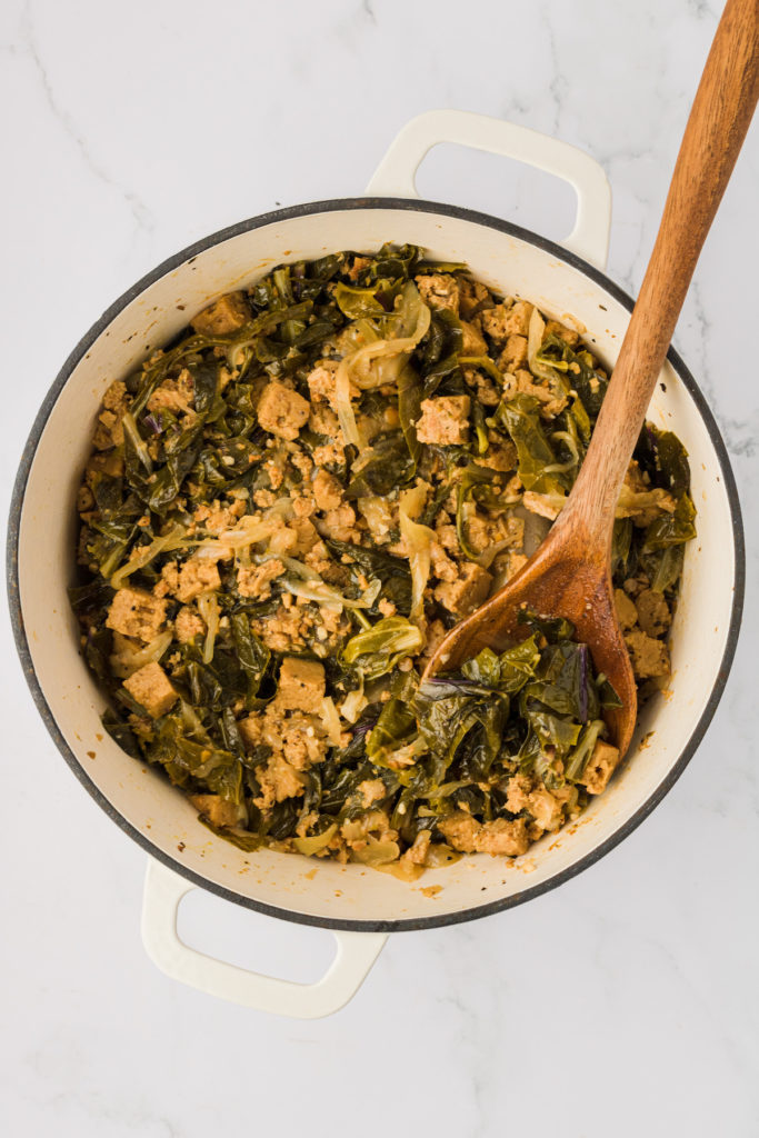 Overhead view of vegan turnip greens in pot with wooden spoon