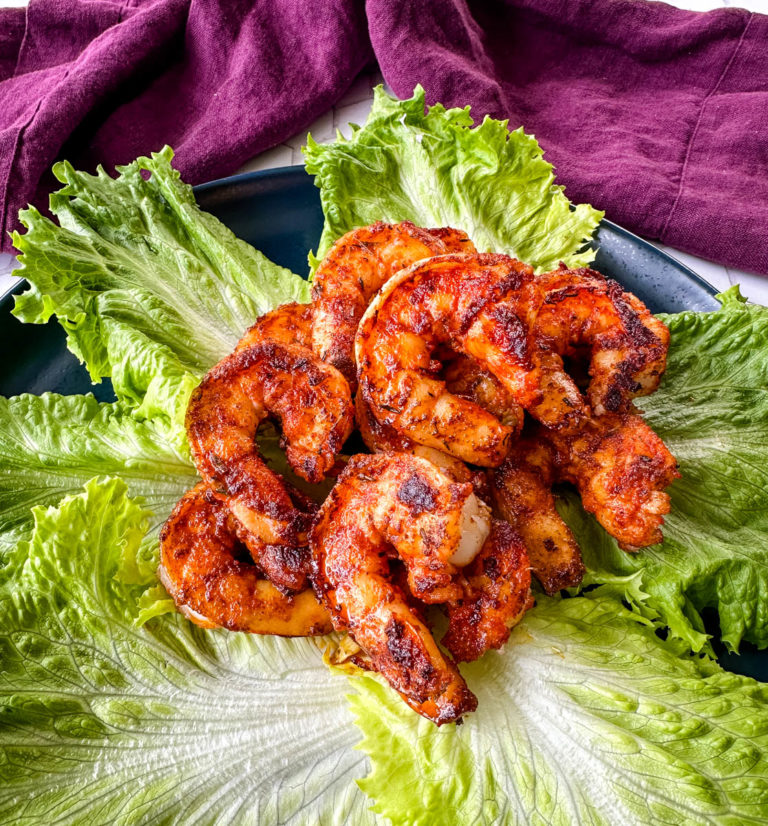 cooked Cajun shrimp on a bed of green leaf lettuce