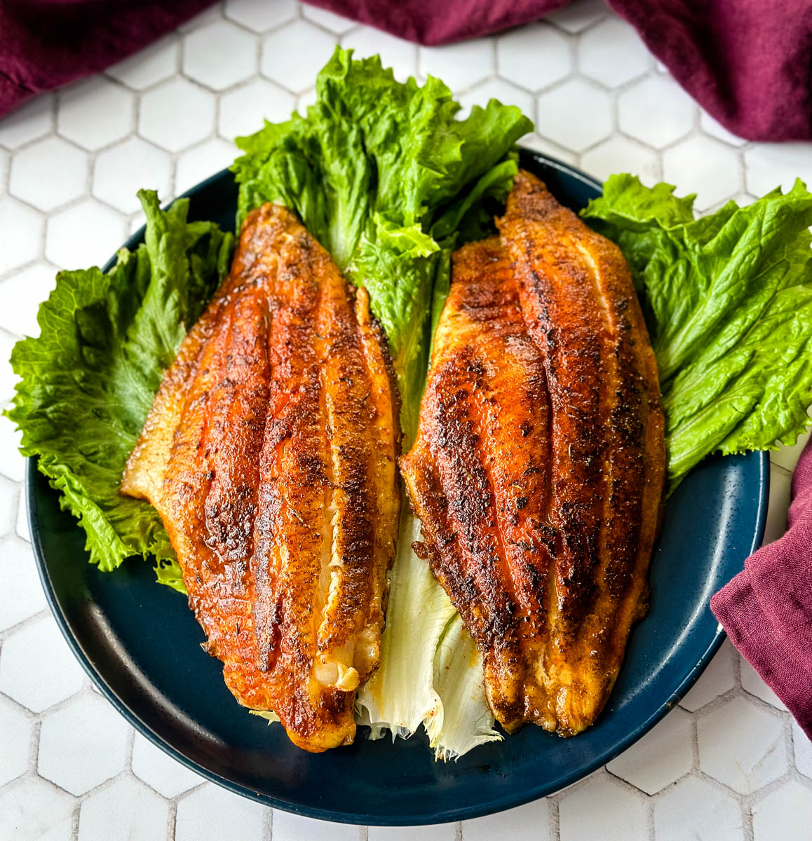 Cajun fish on a bed of lettuce on a blue plate