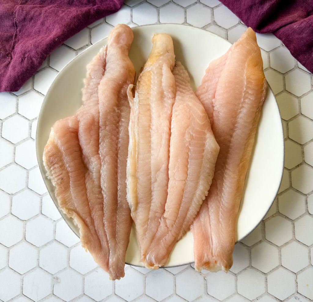 raw whitefish catfish on a white plate