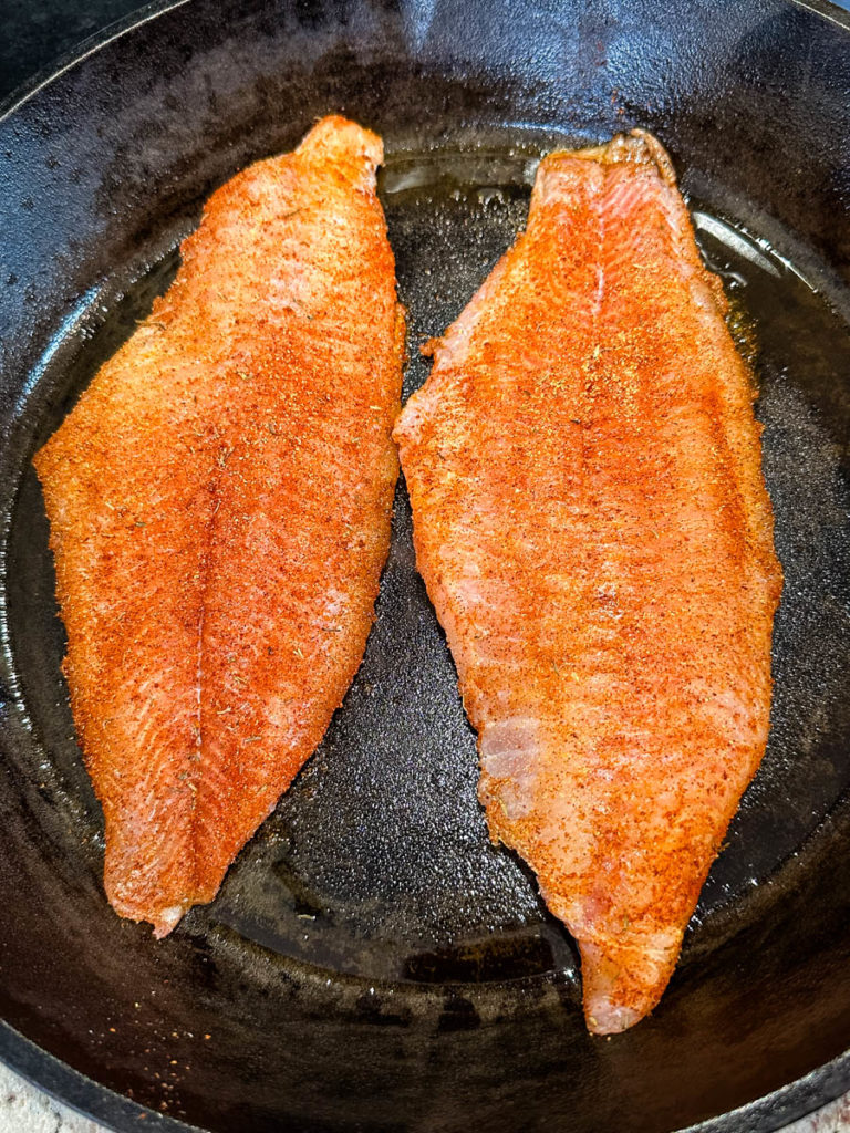 uncooked Cajun fish in a cast iron skillet