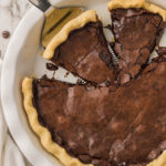 Vegan chocolate chess pie in pie pan with slice on spatula